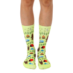 Lime green crew socks with a whimsical camping scene featuring Bigfoot, tents, campfires, and other outdoor elements. [lf]