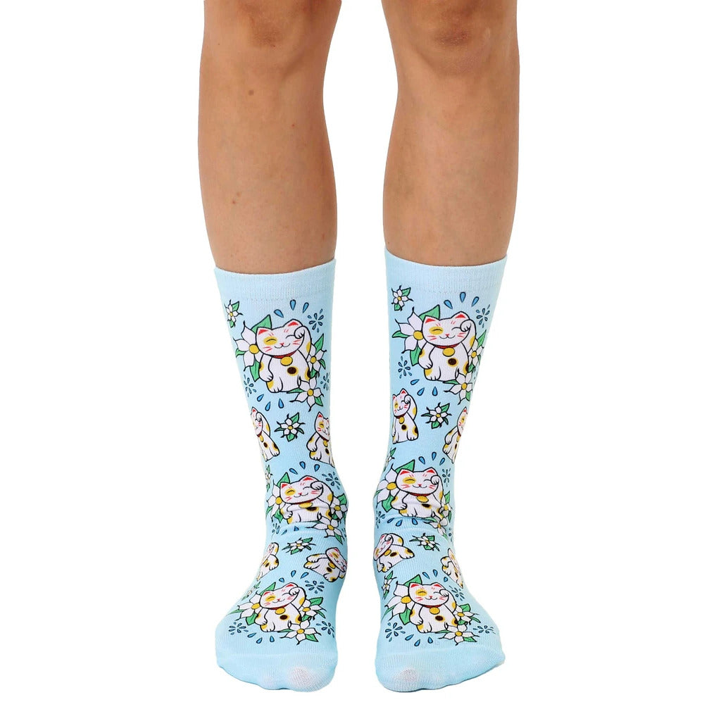 Pair of pastel blue crew socks with a repeating pattern of Maneki Neko (beckoning cat) illustrations and white flowers. [lf]