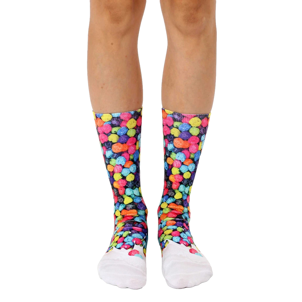 A pair of crew socks with a colorful fruity pebble design on a black background and white toe and heel. [lf]