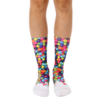 A pair of crew socks with a colorful fruity pebble design on a black background and white toe and heel. [lf]