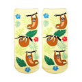Pair of pastel yellow ankle socks featuring illustrated brown tree sloths hanging from branches, surrounded by tropical leaves and hibiscus flowers.