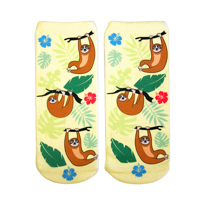Pair of pastel yellow ankle socks featuring illustrated brown tree sloths hanging from branches, surrounded by tropical leaves and hibiscus flowers.