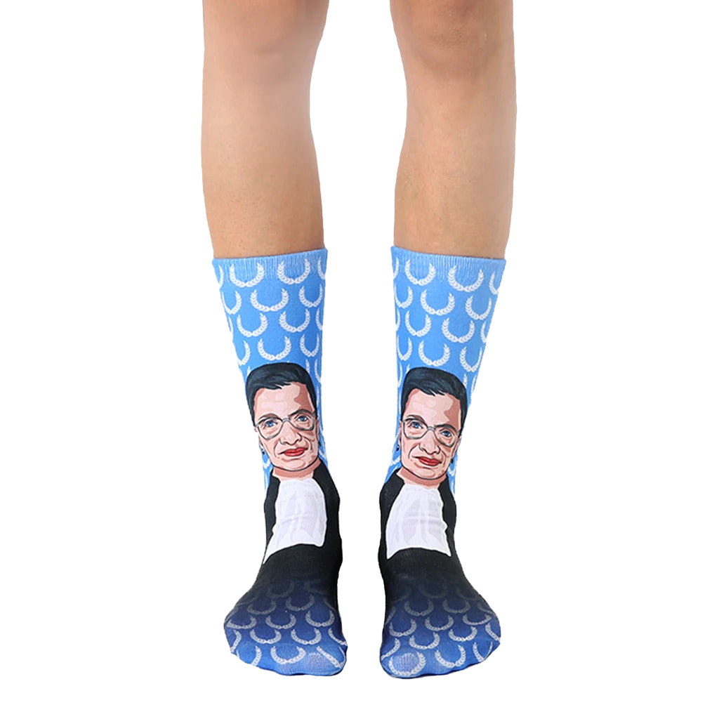 Crew socks in blue featuring a portrait of Ruth Bader Ginsburg.  The background pattern is white laurel wreaths. [lf]