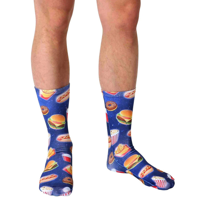 A pair of blue socks with a pattern of various fast food items such as hamburgers, hotdogs, popcorn, and soda.