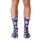 A pair of blue crew socks with a fun pattern of fast food items like burgers, fries, and hot dogs against a galaxy-printed background. [lf]