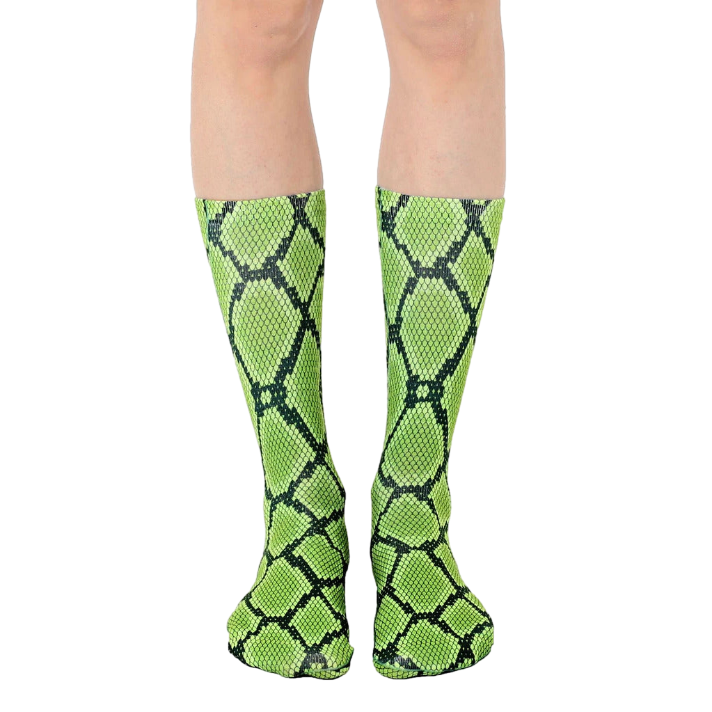 Pair of lime green and black snakeskin-print crew socks shown on a model's legs. [lf]