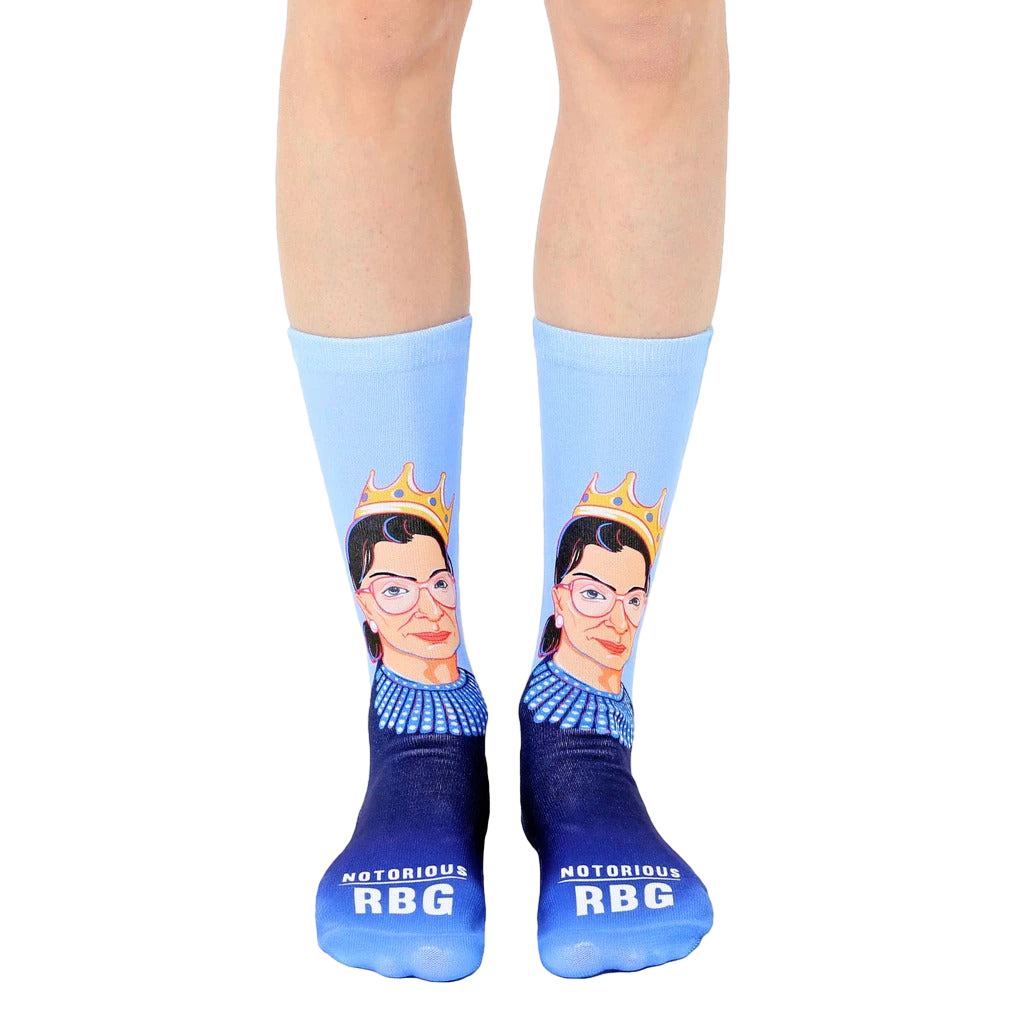 A pair of women's crew socks in light blue and navy blue. The socks feature a portrait of Ruth Bader Ginsburg wearing a crown. [lf]