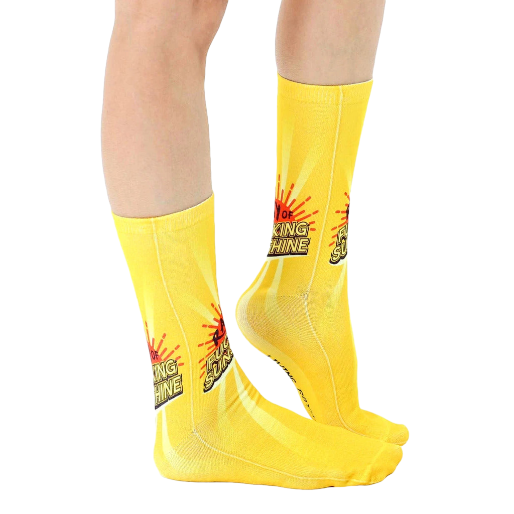 Lifestyle shot showing the socks on a person's legs;  bright yellow socks with sun graphic and phrase. [lf]