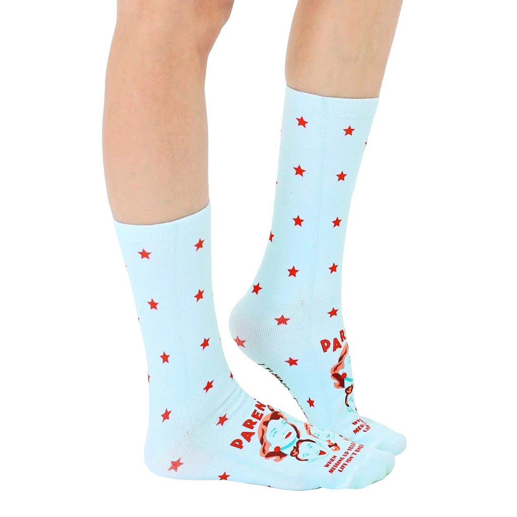 Lifestyle shot of a person wearing the light blue crew socks with red stars and a humorous parenting quote. [lf]