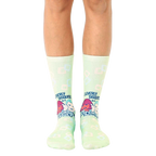 Pair of light green crew socks with a retro design featuring cartoon characters and the text 'Cleverly Disguised as a Responsible Adult'. [lf]