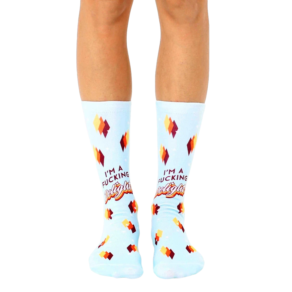 Pair of light blue crew socks with a retro-style design and the phrase "I'm a Fucking Delight" in orange and brown lettering. [lf]