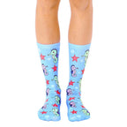 A pair of light blue crew socks featuring a pattern of cute seahorses and red starfish. [lf]