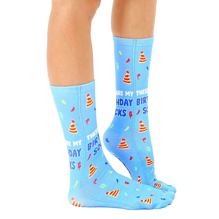 A pair of blue socks with a pattern of multi-colored party hats and white text that reads, 