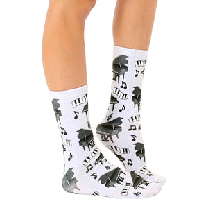 A pair of white socks with a pattern of black pianos and musical notes.