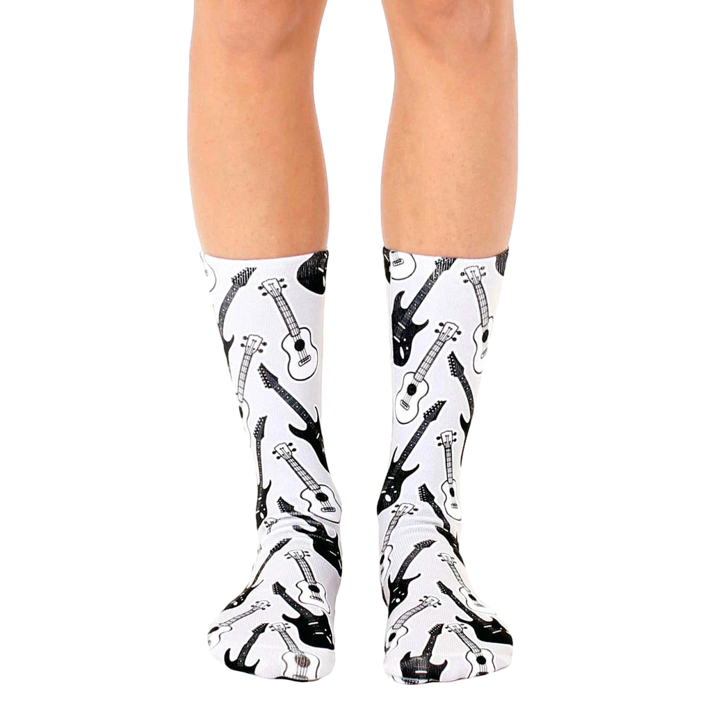 A pair of white crew socks with a repeating pattern of black and white electric and acoustic guitars. [lf]
