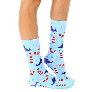 A pair of blue socks with a pattern of whales, crabs, and lighthouses.