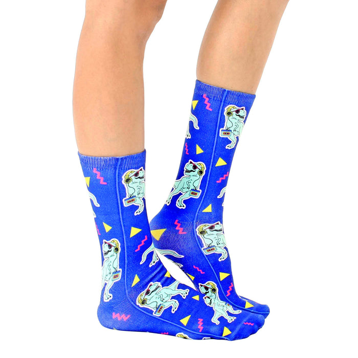 A person is shown wearing a pair of blue socks with a pattern of cartoon dinosaurs wearing sunglasses and listening to boomboxes.