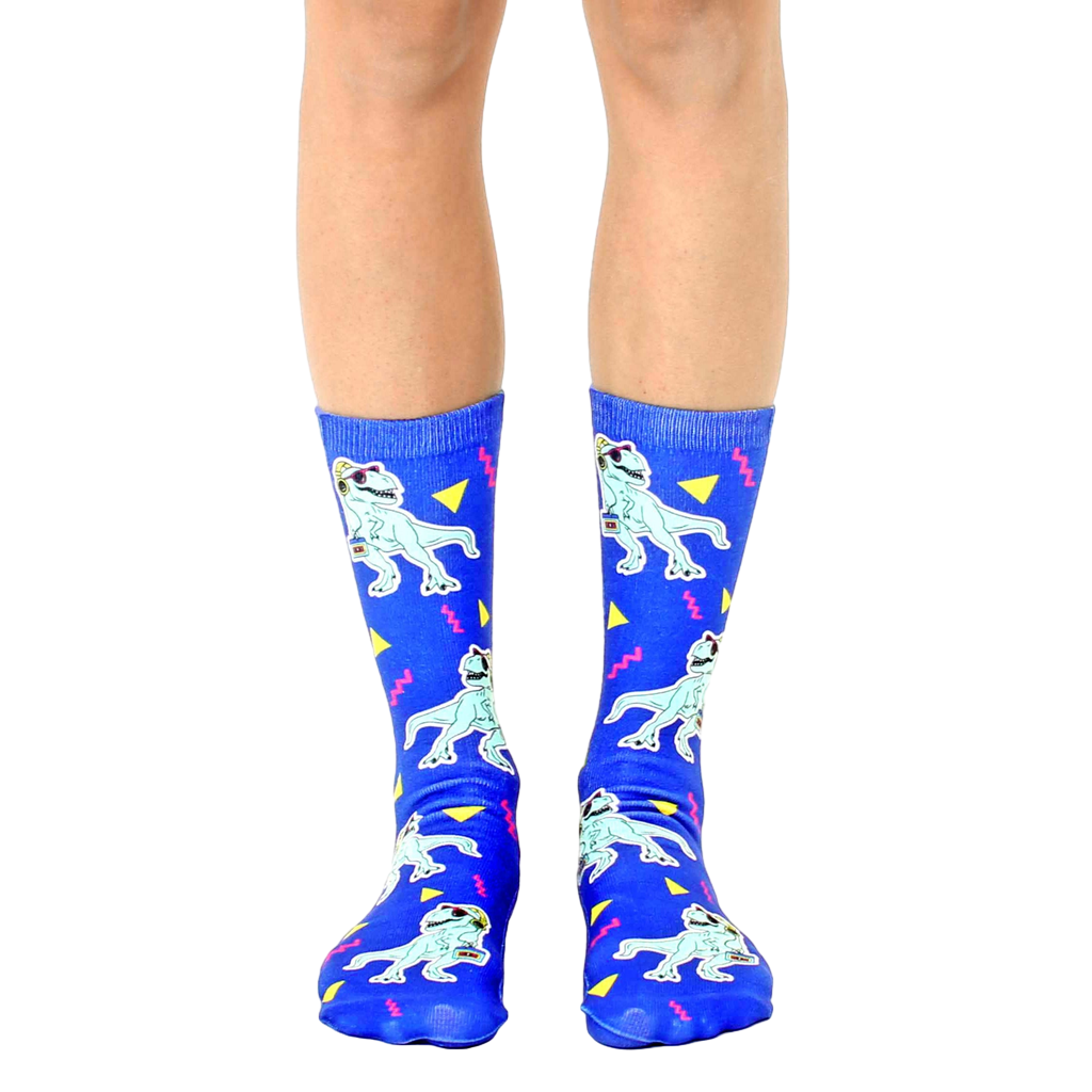 A pair of blue crew socks with a fun 90s-themed design.  The socks feature cartoon dinosaurs wearing sunglasses and boomboxes, along with yellow triangles and pink zigzags. [lf]