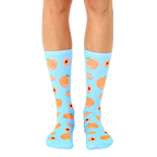 Pair of light blue crew socks with an all-over print of peaches and peach slices. [lf]