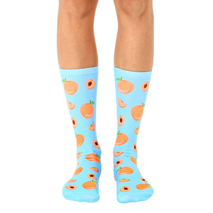 blue crew socks with allover cartoon peach pattern in orange with red centers and green leaves. for men and women.  