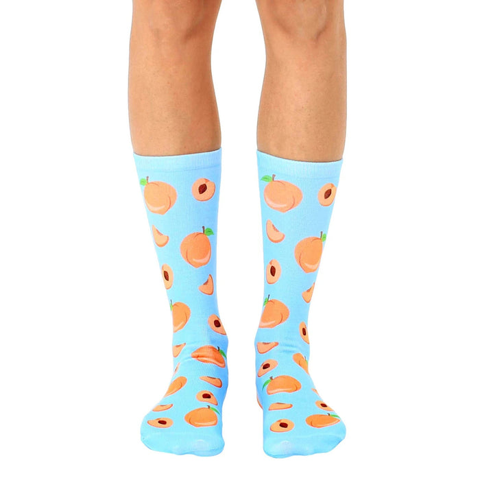 blue crew socks with allover cartoon peach pattern in orange with red centers and green leaves. for men and women.  