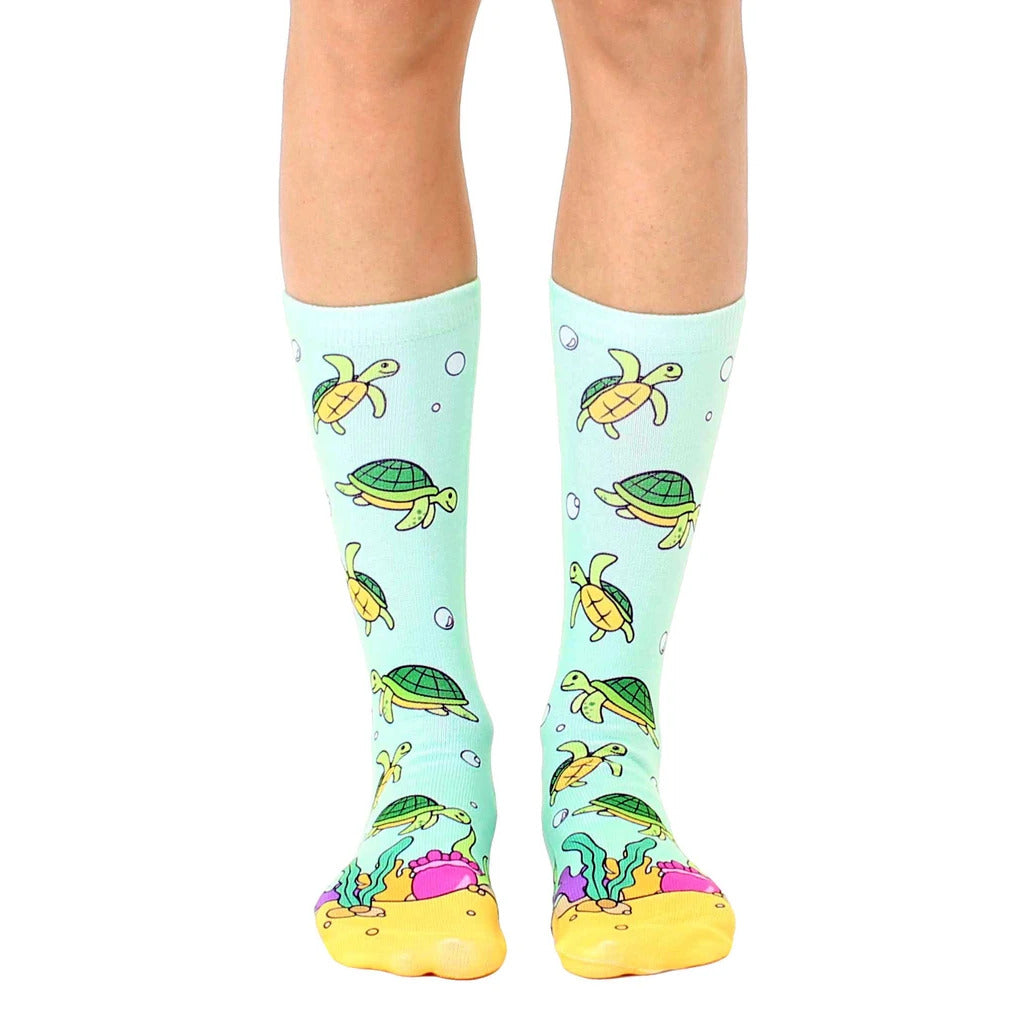 Crew socks in teal featuring a pattern of cartoon sea turtles, bubbles, and yellow-orange coral reef at the bottom. [lf]