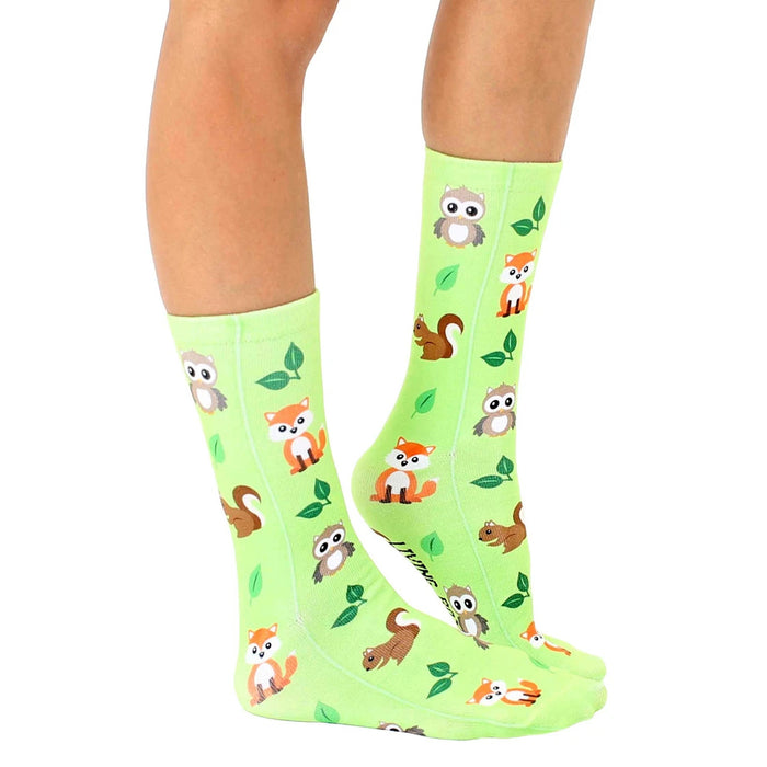 A pair of green socks with a pattern of cartoon woodland creatures and green leaves.