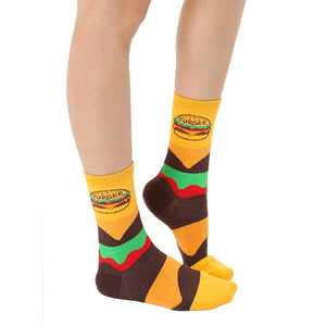 A pair of yellow baby socks with a hamburger graphic on the front and non-skid soles.