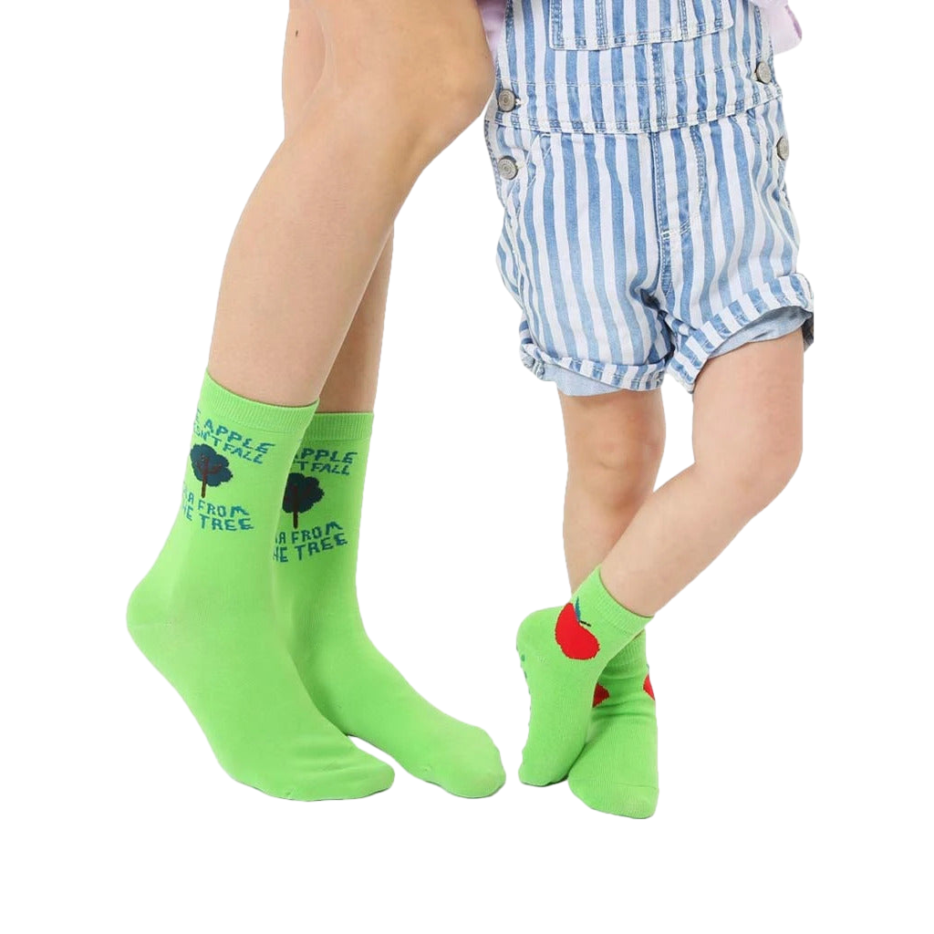 Adult and child lime green crew socks. Adult socks feature 'The apple doesn't fall far from the tree' text and a small tree graphic. Child socks have a red apple graphic. [lf]