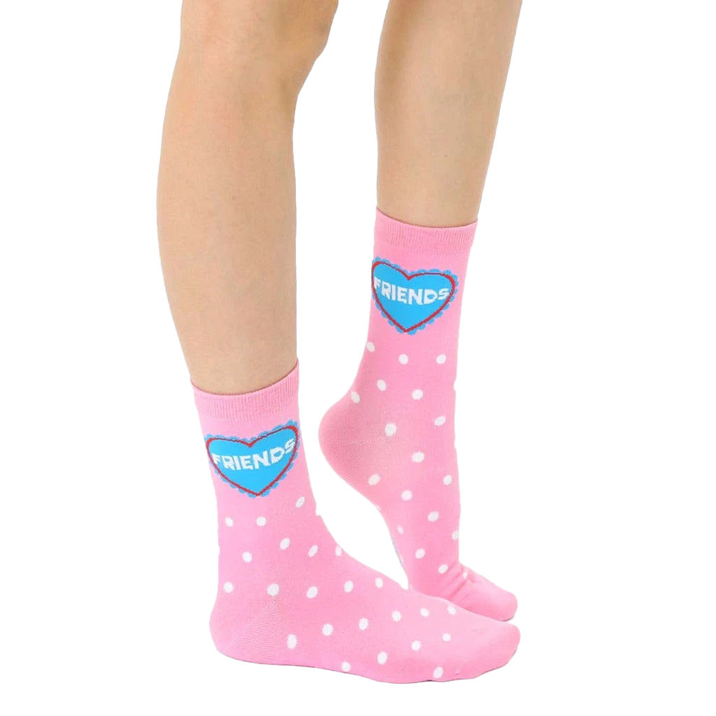 Close-up of adult-sized pink polka dot socks with a blue heart that says 'Friends'. [lf]