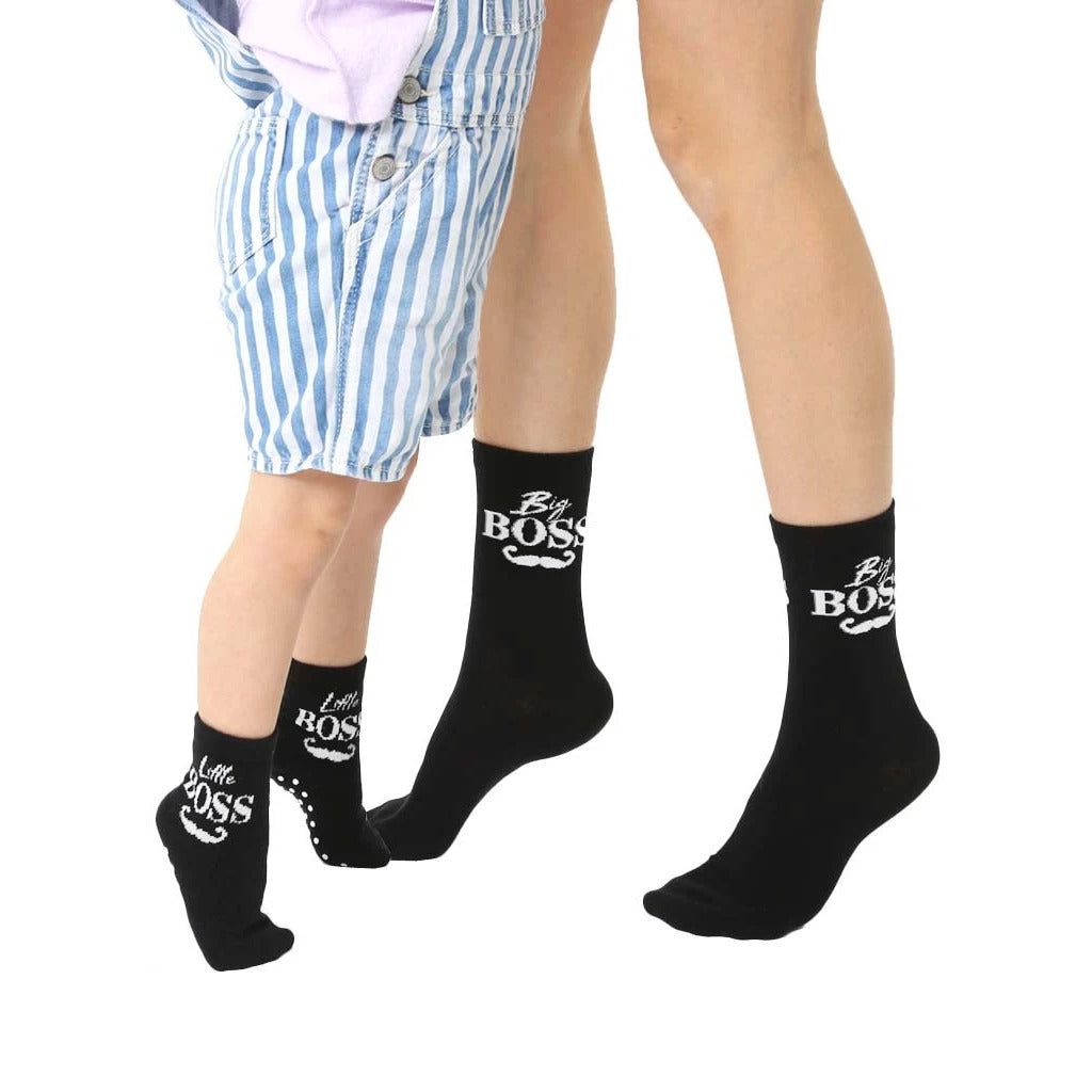 Adult and child black crew socks.  Adult socks say 'Big Boss' with a mustache. Child socks say 'Little Boss' with a mustache and grippers. [lf]