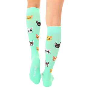 A pair of mint green knee-high socks with a pattern of cartoon cat faces in various colors.