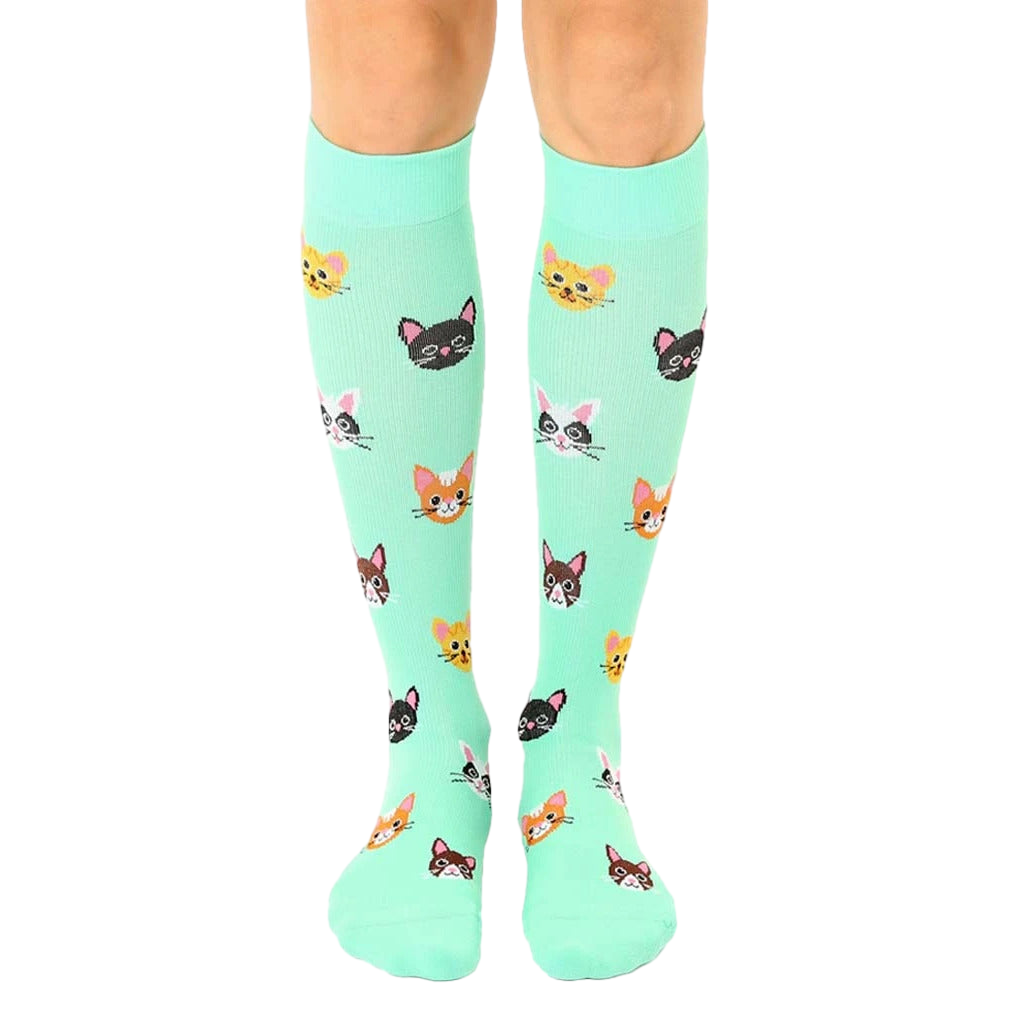 Pair of mint green knee-high socks with a pattern of cute, colorful cat faces. [lf]