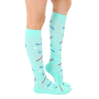 Side view of a person wearing a pair of mint green knee-high Dentist socks. [lf]