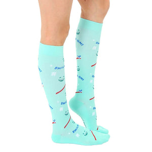 A pair of light blue knee-high socks with a pattern of cartoon faces with the words 