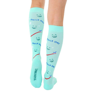 A pair of light blue knee-high socks with a pattern of cartoon faces with the words 
