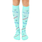 Pair of mint green knee-high socks featuring smiling faces, toothbrushes, and the text 'Smile On!' [lf]