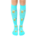 Pair of turquoise knee-high socks with a pattern of pills, beakers, and the text "Best Medicine." [lf]