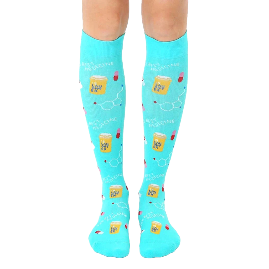Pair of turquoise knee-high socks with a pattern of pills, beakers, and the text "Best Medicine." [lf]