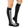 Lifestyle shot of a person wearing black knee-high skeleton socks. The socks are slightly angled, showing off the design. [lf]