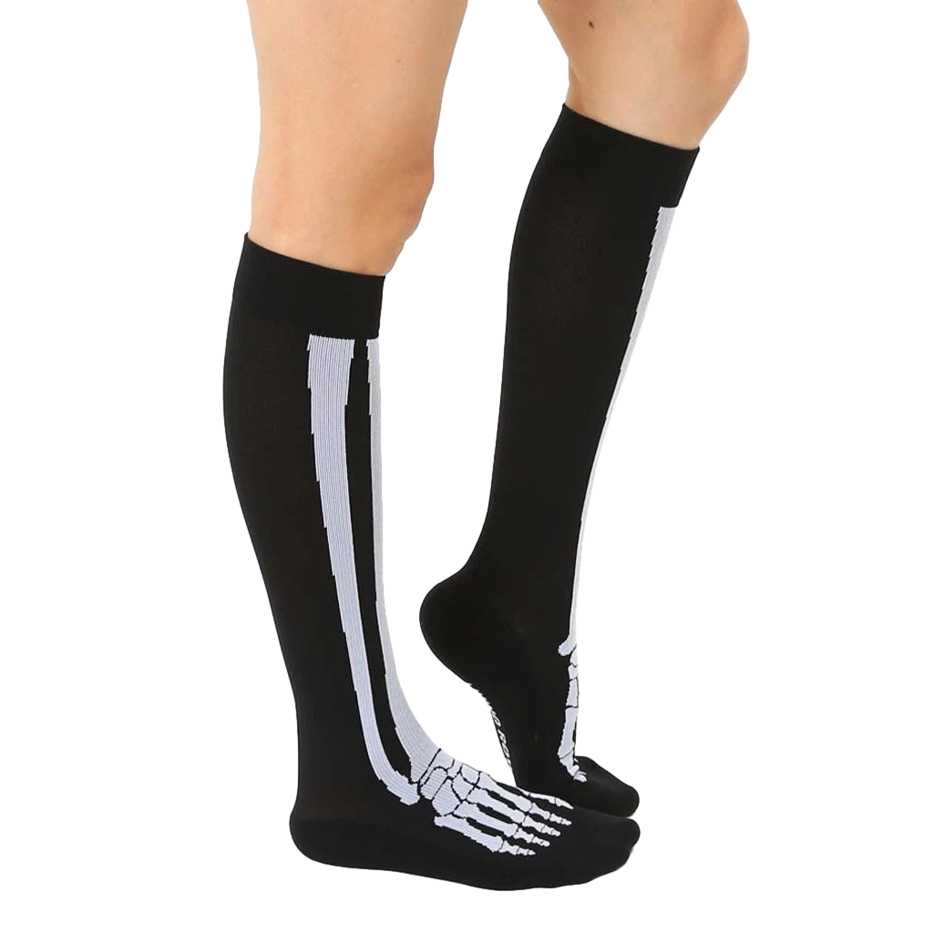 Lifestyle shot of a person wearing black knee-high skeleton socks. The socks are slightly angled, showing off the design. [lf]
