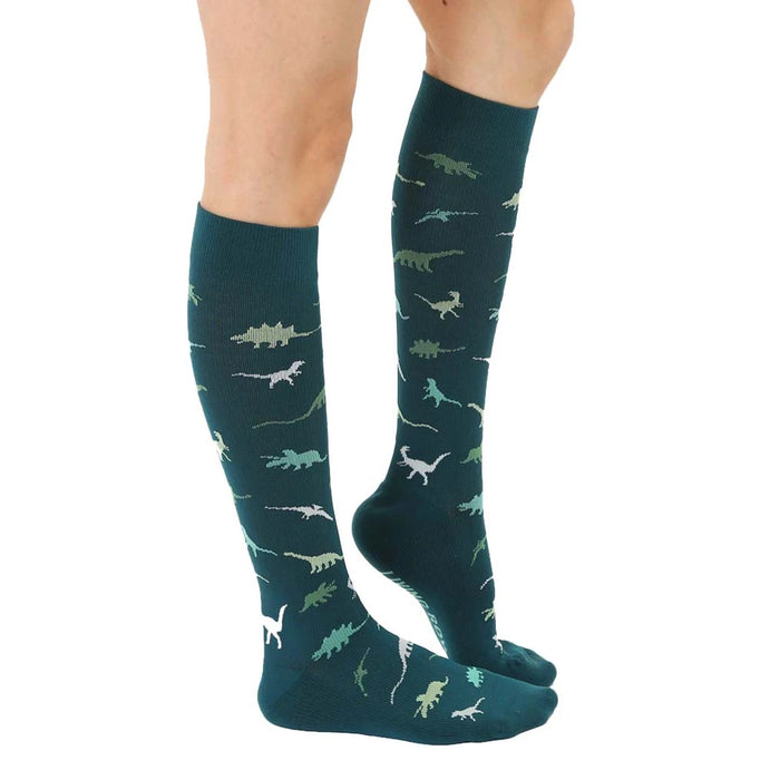 A pair of dark green knee-high socks with a pattern of small dinosaurs in lighter green.