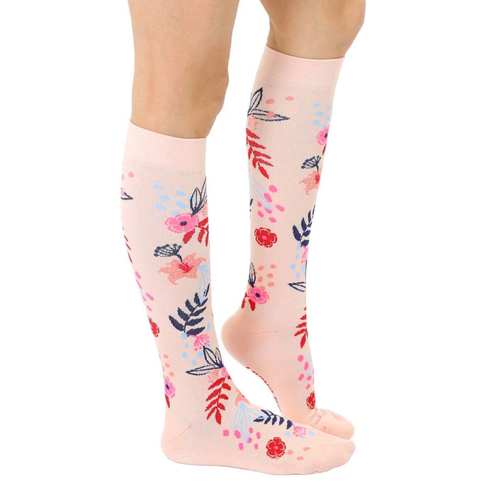 A pair of pink knee-high compression socks with a floral pattern. The socks have the words 