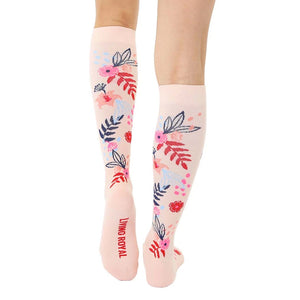 A pair of pink knee-high compression socks with a floral pattern. The socks have the words 