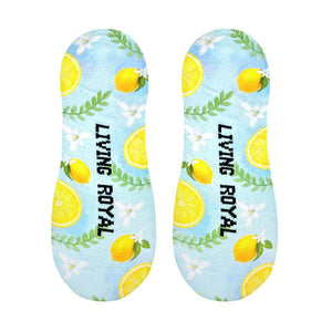A pair of blue no-show socks with a pattern of lemons, leaves, and flowers. The Living Royal logo is printed on the bottom of each sock in black.