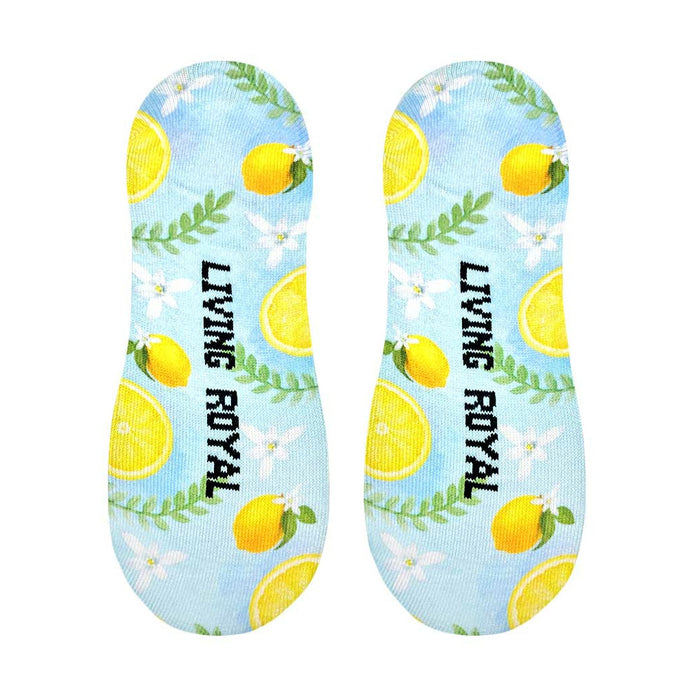 A pair of blue no-show socks with a pattern of lemons, leaves, and flowers. The Living Royal logo is printed on the bottom of each sock in black.