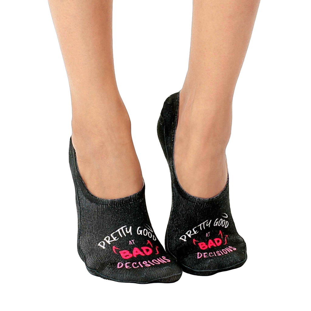 Pair of black no-show socks with a pink 'Pretty good at bad decisions' slogan and small devil horns graphic. [lf]