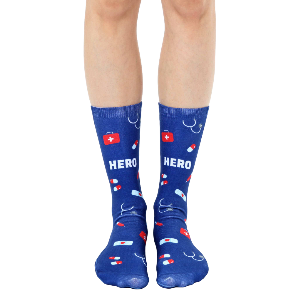 Pair of navy blue crew socks with a fun design featuring red medical icons (pills, bandages, stethoscope) and the word HERO. [lf]