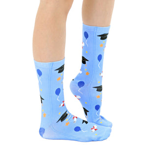 A pair of blue socks with a pattern of graduation caps, balloons, stars, and diplomas.