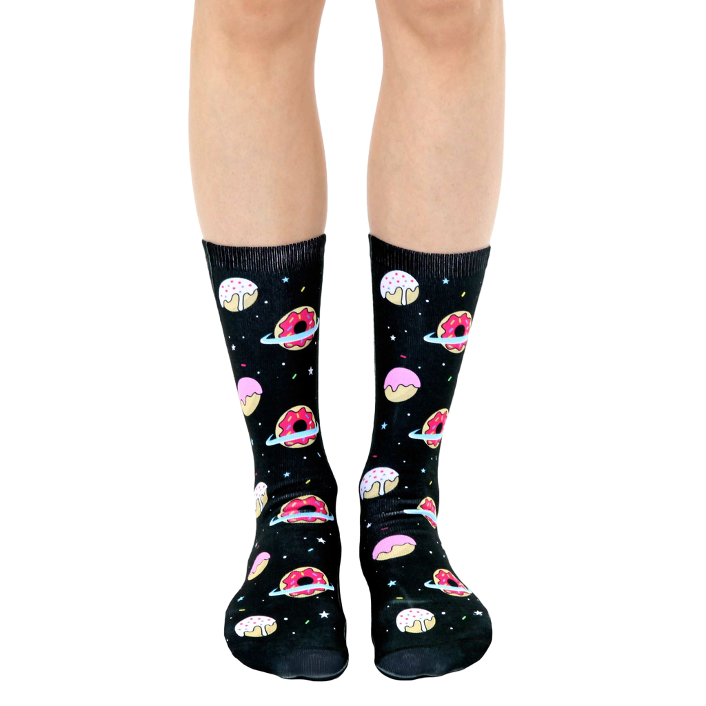 Crew socks in black with pink and white donut designs orbiting like planets against a starry background. [lf]
